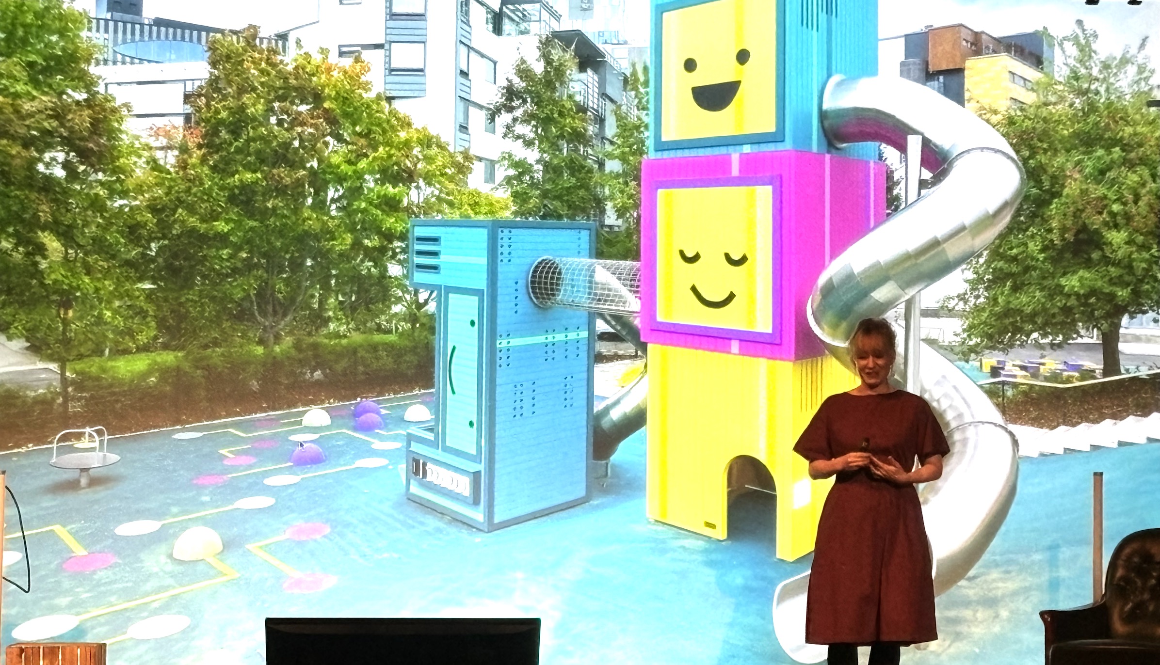 Linda in front of a slide with the colorful computer playground she designed for kids
